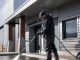 Professional pressure washing a concrete entrance beside a commercial building in Whitehorse