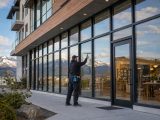 Professional window cleaner using a squeegee on commercial windows in Whitehorse